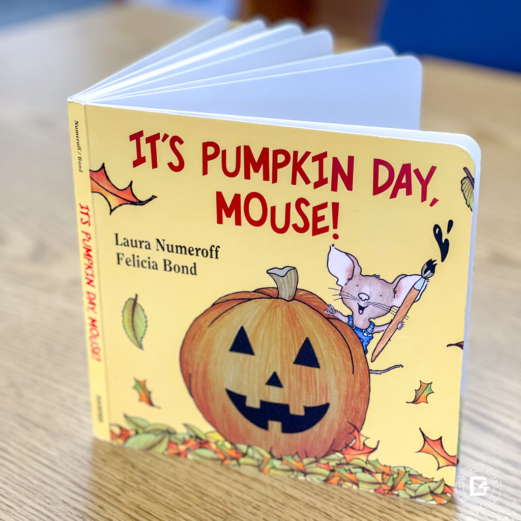 Close-up of the book It’s Pumpkin Day, Mouse! by Laura Numeroff and Felicia Bond on a wooden table.
