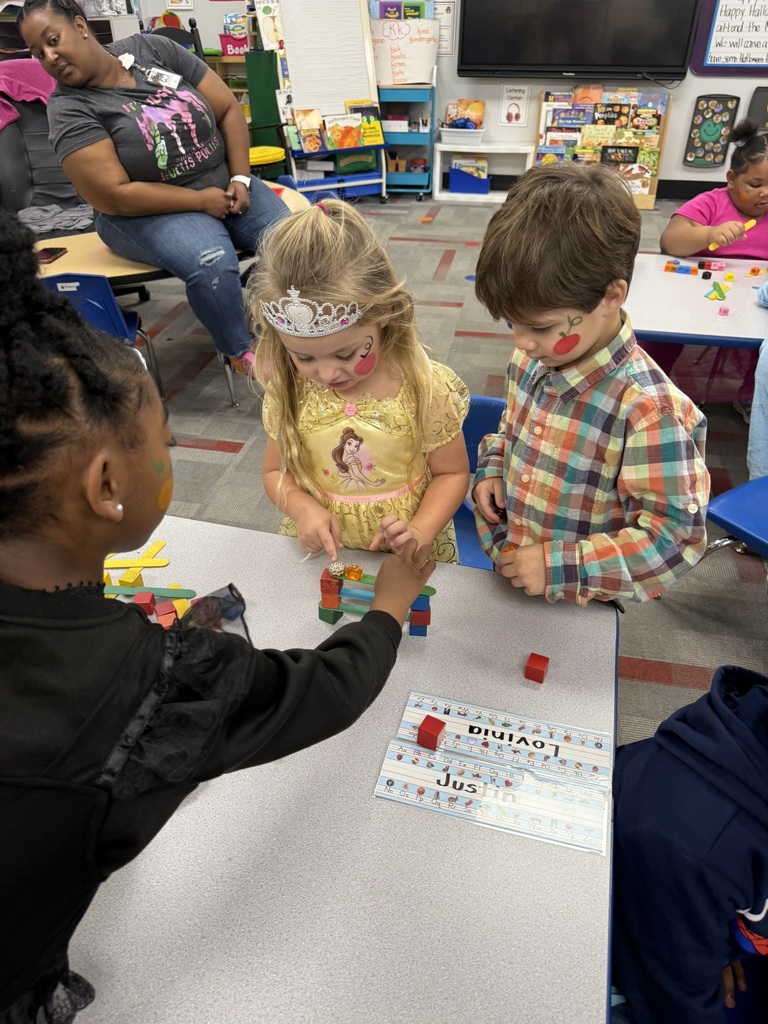 Students in Mrs. Forest’s Pre-Kindergarten class at Williams Memorial Elementary School work together on a Halloween-themed STEM challenge. Each group uses colorful blocks, linking cubes, and craft sticks to build a gate for five little pumpkins after reading Five Little Pumpkins. Children dressed in costumes—princesses, superheroes, and storybook characters—focus intently as they design, test, and adjust their creations, demonstrating teamwork, problem-solving, and persistence.