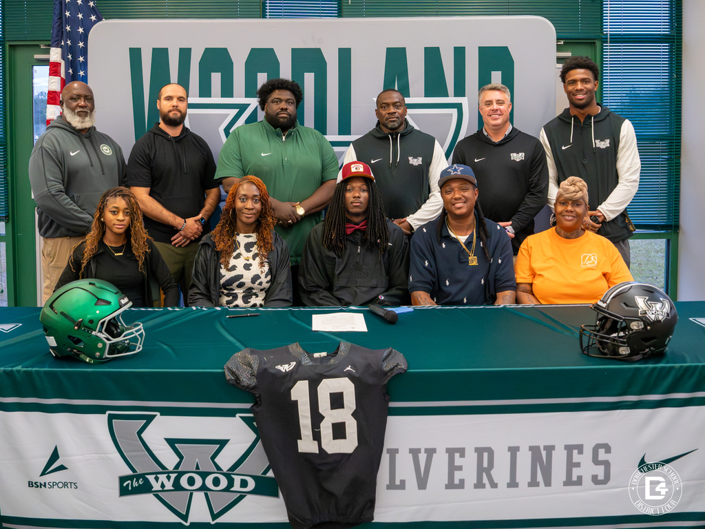 Coaches line up behind Jaemin Pinckney and his family for a group photo at the signing ceremony.