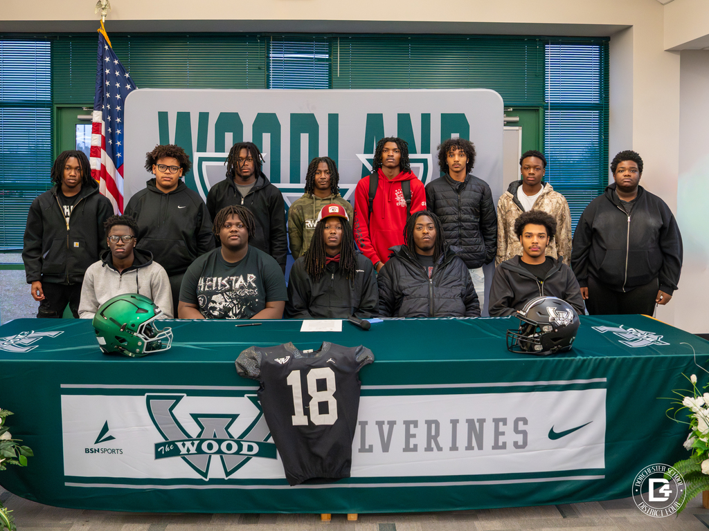 Jaemin Pinckney sits with his teammates behind him for a group photo at the signing table.