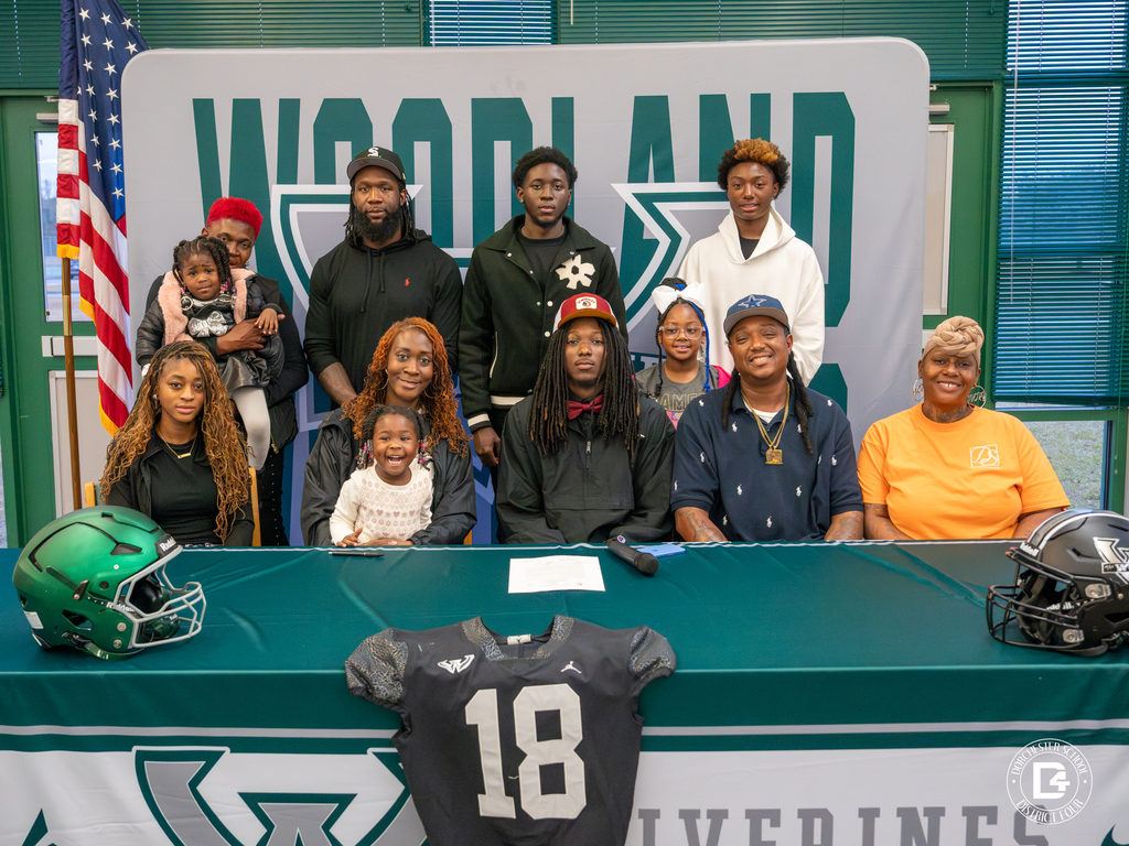 A full family photo with Jaemin Pinckney at the center, everyone gathered behind the signing table with his jersey displayed.