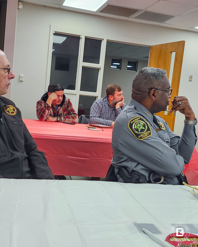 Local law enforcement and community partners sit at a table listening during a Dorchester School District Four mentoring program meeting focused on student support and collaboration.