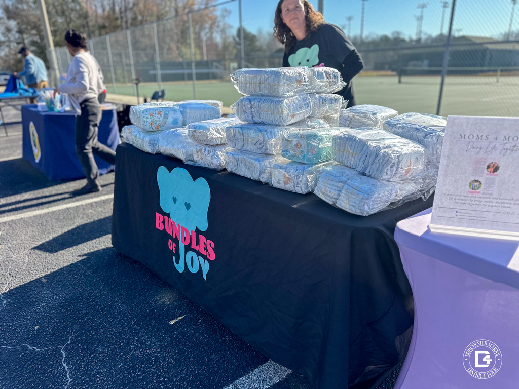 A Bundles of Joy table displays stacks of donated diapers and baby supplies for families attending Christmas at DD4.