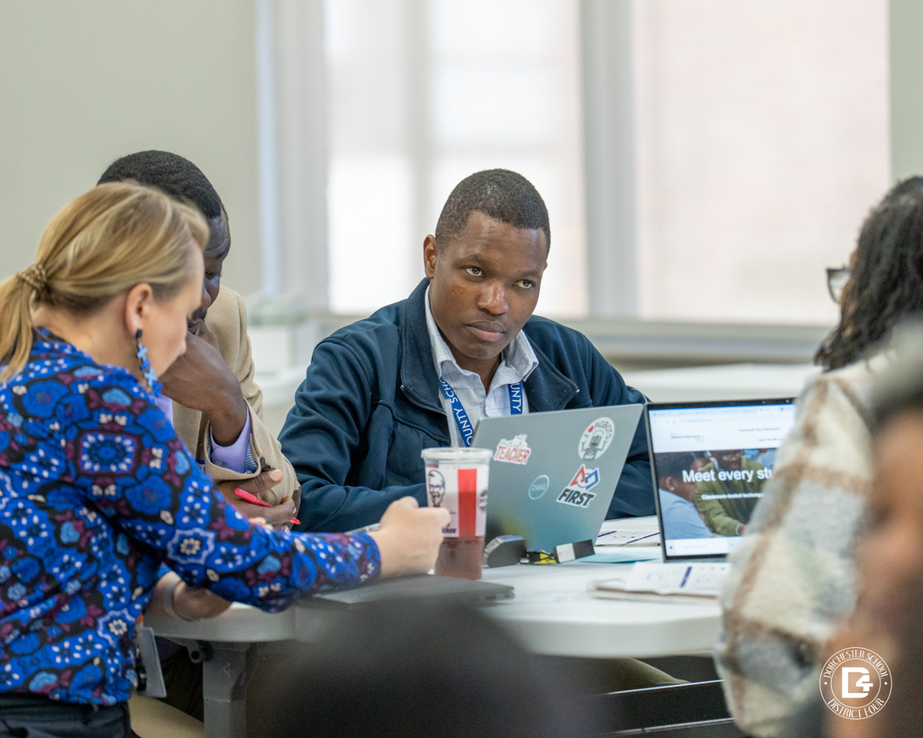 Small group discussion at a table as an educator listens and takes notes during a professional development session.