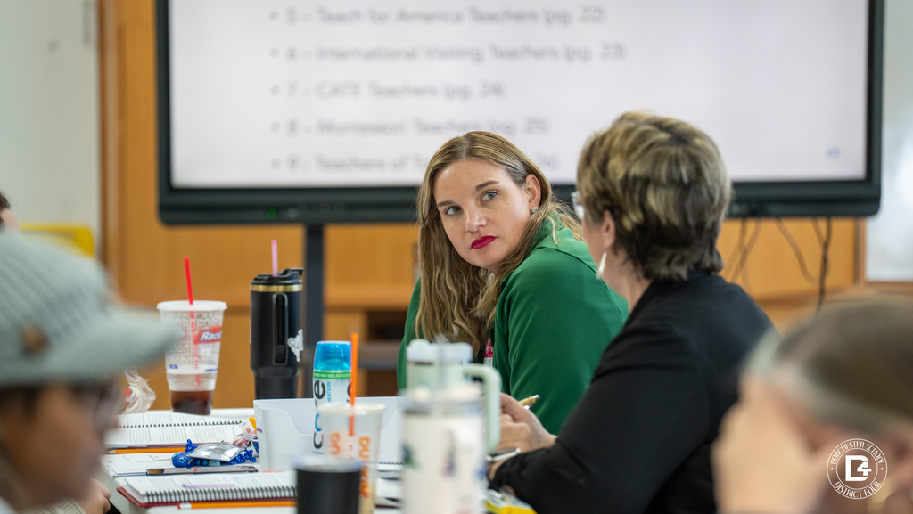 A teacher reviews a workbook and training materials while seated at a table during Dorchester School District Four mentor training.