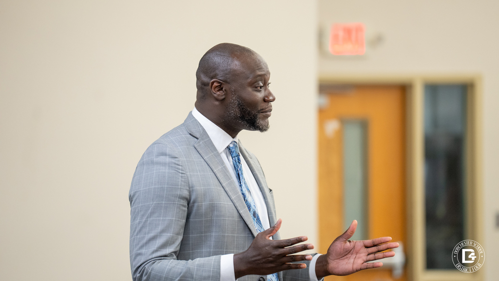 A Woodland High School administrator speaks and gestures during a Wolverines of the Month recognition gathering. (principal white)