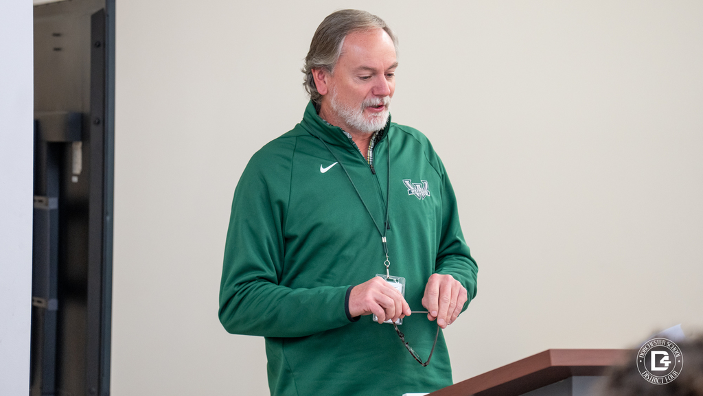Mr Connelly stands at a podium addressing attendees during the Wolverines of the Month celebration.