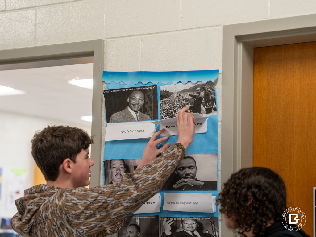 A student lifts a flap on a Martin Luther King Jr. themed classroom door display, revealing printed research beneath the images.