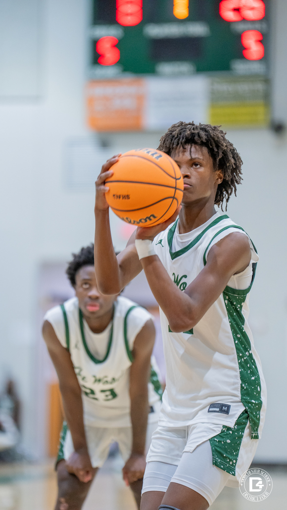 Jhailen Herrin sets at the free throw line with the ball raised in shooting position, eyes locked on the rim as a teammate waits along the lane.