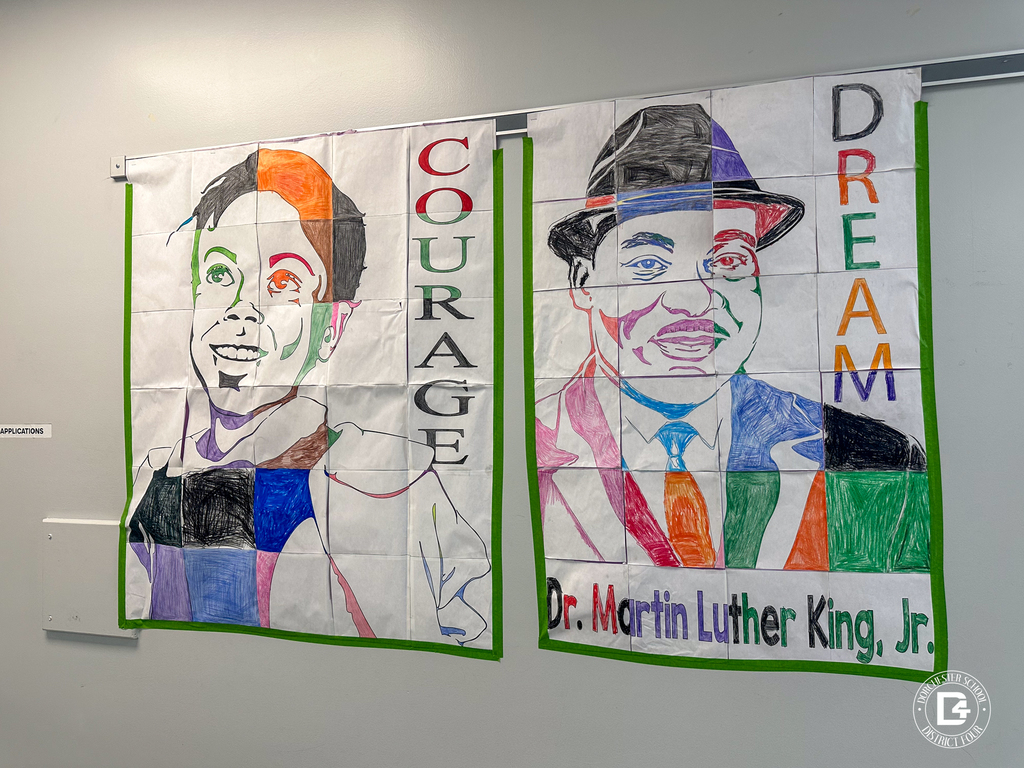 Two large hallway portraits displayed side by side. The left mural reads “COURAGE” and shows a colorful stylized portrait. The right mural reads “DREAM” and features a colorful portrait of Dr. Martin Luther King Jr., with his name written along the bottom.