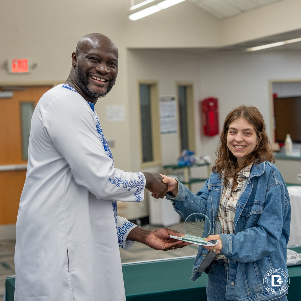 Administrator presents a glass Wolverine of the Month award to a female staff member during the morning recognition.
