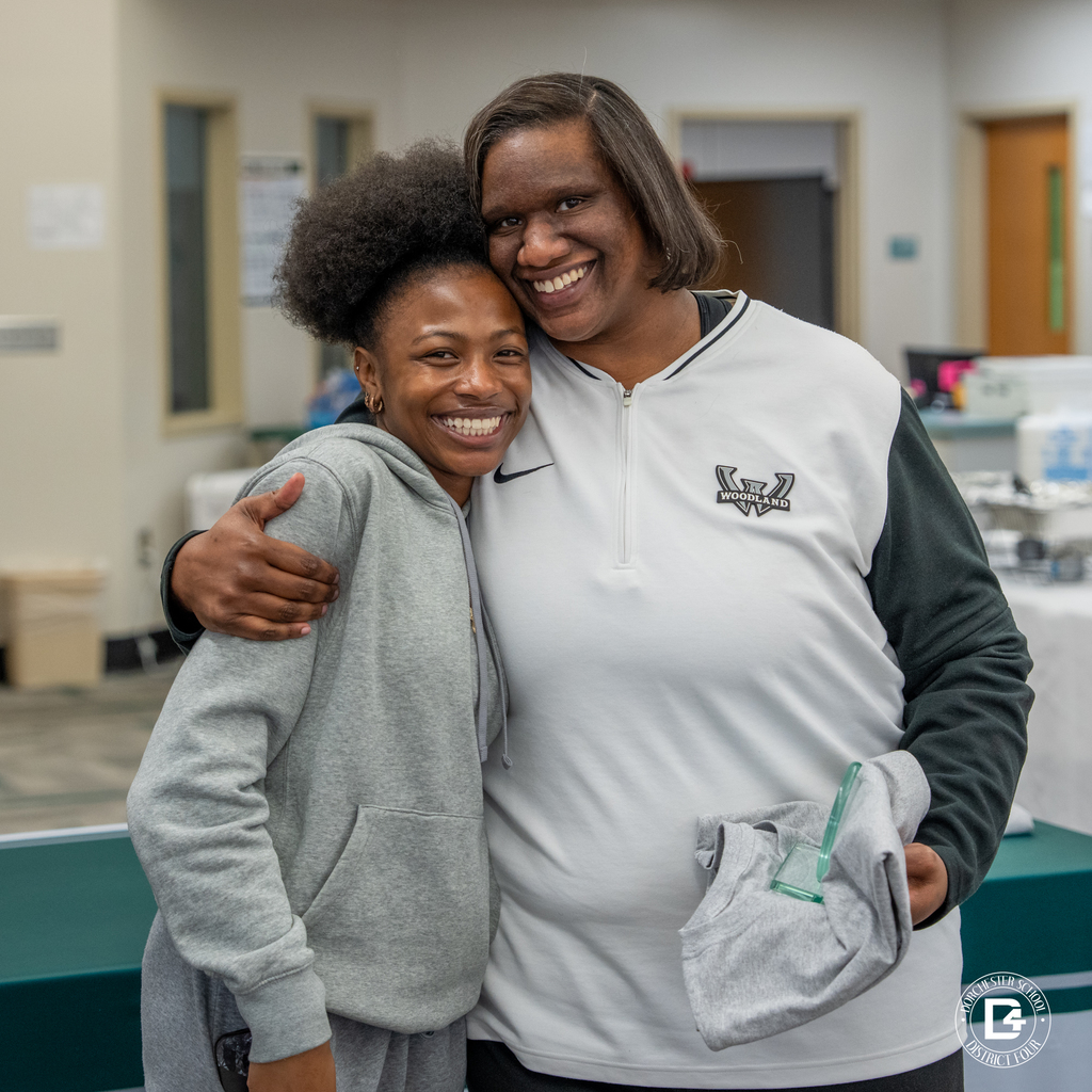 Female staff member embraces a smiling female student after receiving Wolverine of the Month honors.