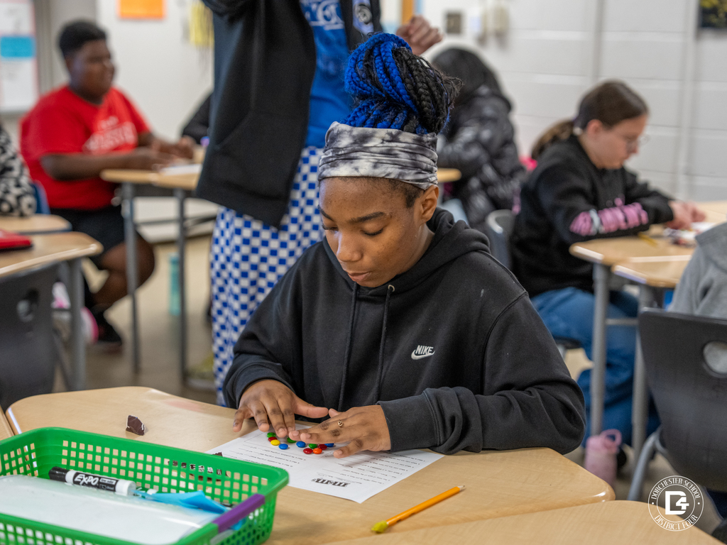 Student carefully arranges M&M’s by color on a worksheet while completing a probability activity.