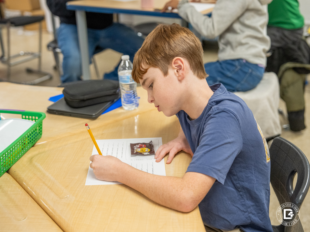 Student leans over a desk writing answers on a worksheet while working through a math assignment during Mrs. Pafford’s class.