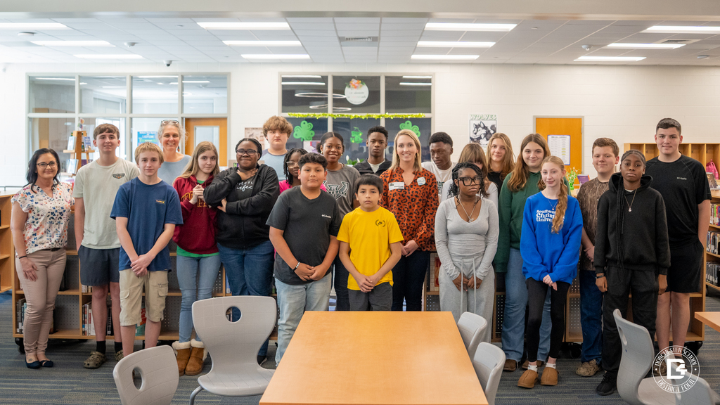 Group photo of Mrs. Weather’s ProTeam students and visiting speaker standing together in the Woodland Middle School library.