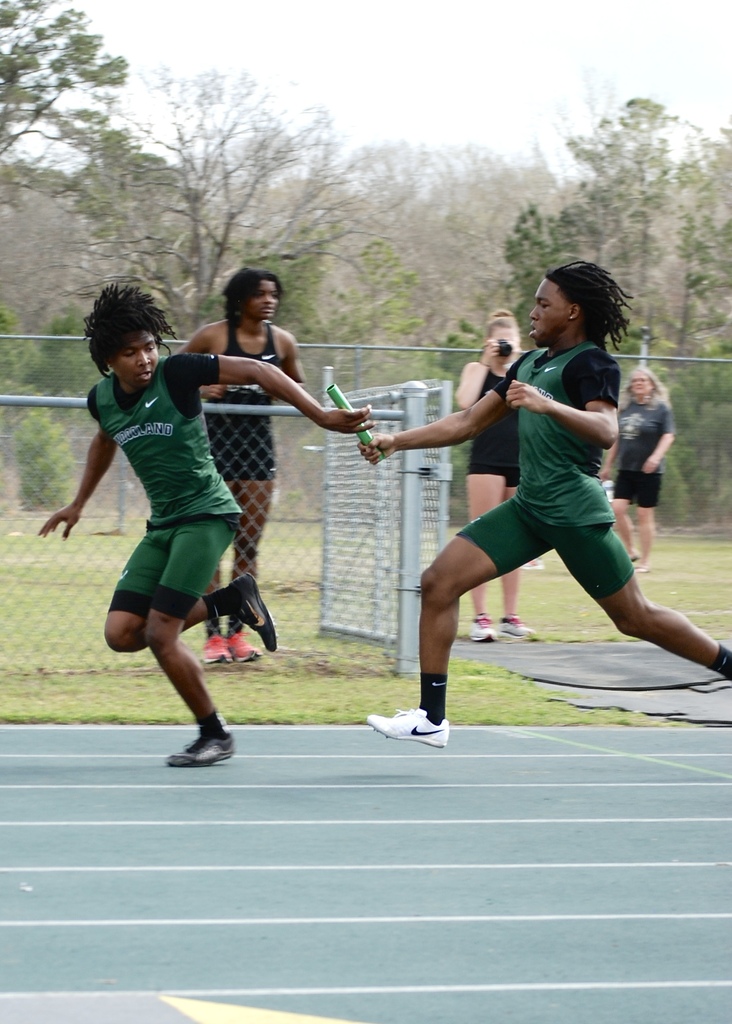Two Woodland High School runners exchange the baton during a relay race on the track