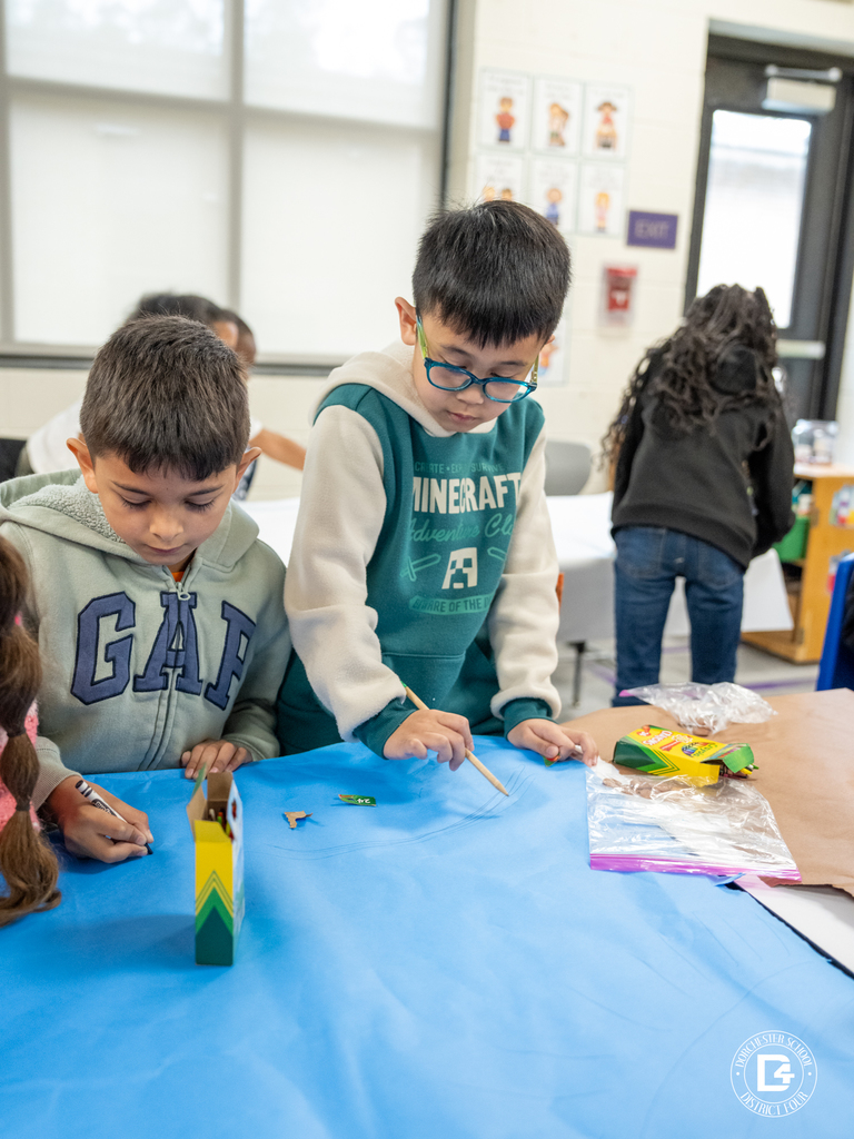 Students working together at a table using crayons and paper to create ecosystem drawings.