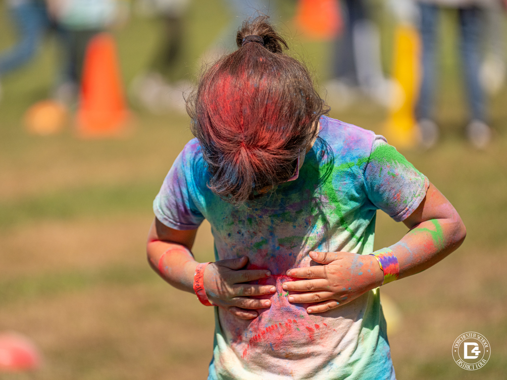 Student looking down at their shirt covered in multicolored powder after participating in the Clay Hill Elementary Color Fun Run.