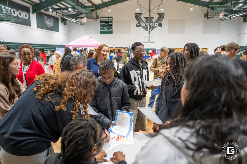 Visiting 8th grade students crowd around club tables in the WHS gymnasium, reviewing information and signing up for interest sheets during the club fair portion of Preview Day.
