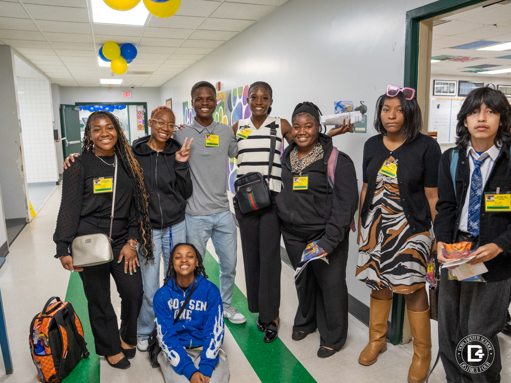 Group of Woodland High School students wearing name badges pose together in a hallway during the L.A.W. event, smiling and holding materials from the day.