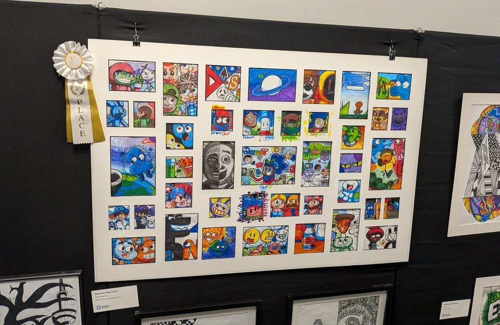  Quentin Barnwell's artwork, Que-niverse, displayed on a black exhibition panel at Charleston Southern University. The large piece features a colorful grid of individually drawn cartoon characters and scenes in marker, ink, and colored pencil. A white and gold 3rd Place ribbon is pinned to the upper left corner of the artwork.