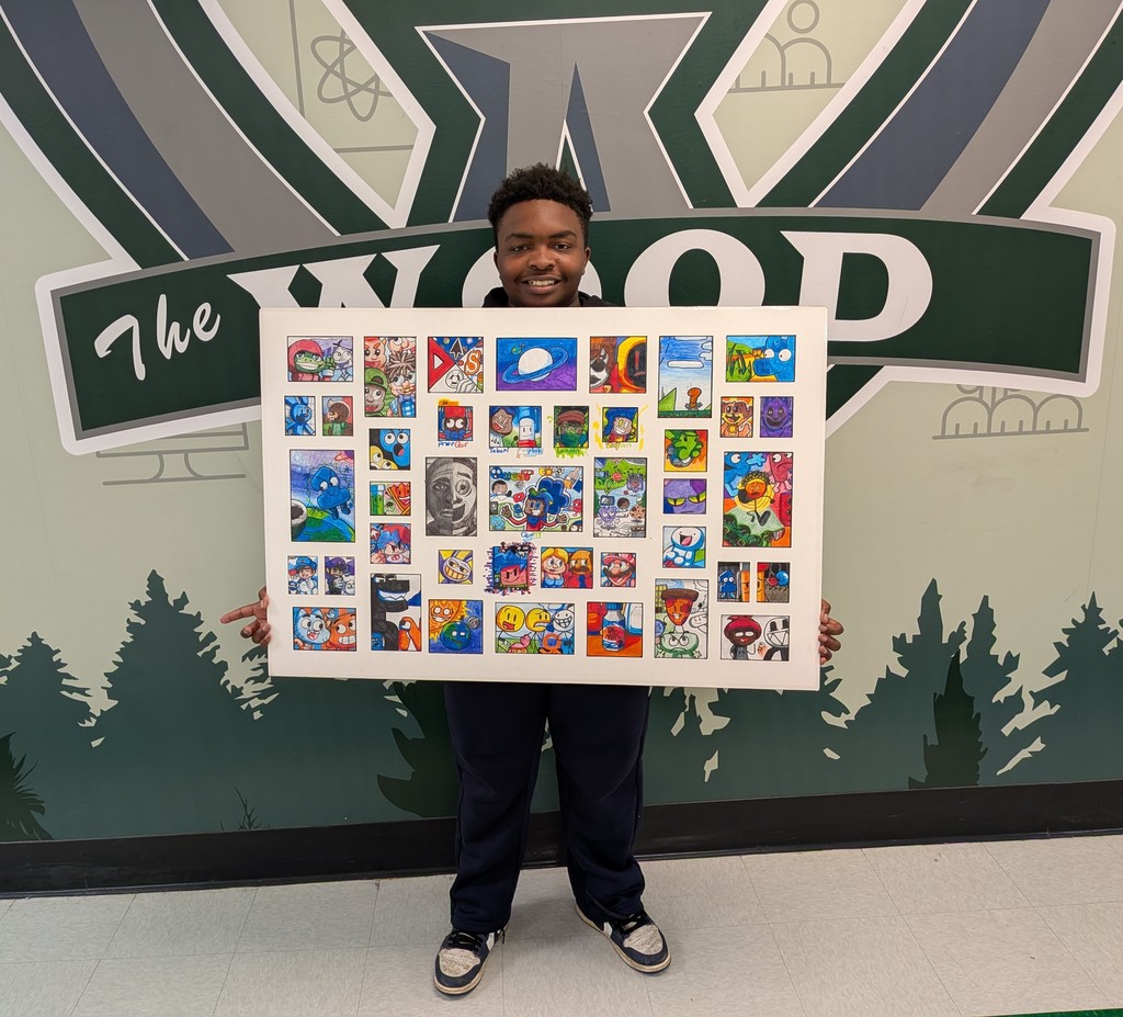 Quentin Barnwell stands in front of the Woodland High School logo holding his award-winning artwork, Que-niverse — a large board filled with a colorful grid of hand-drawn cartoon characters created in marker, ink, and colored pencil.