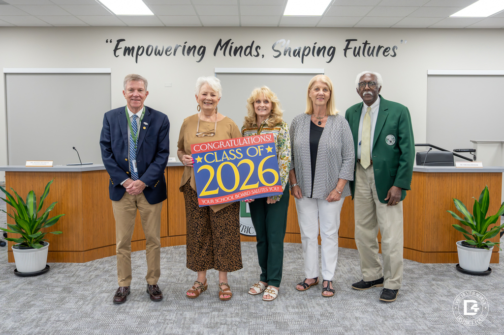 Members of the Dorchester School District Four Board of Trustees stand together in the district boardroom holding a sign that reads, “Congratulations Class of 2026. Your School Board Salutes You.”