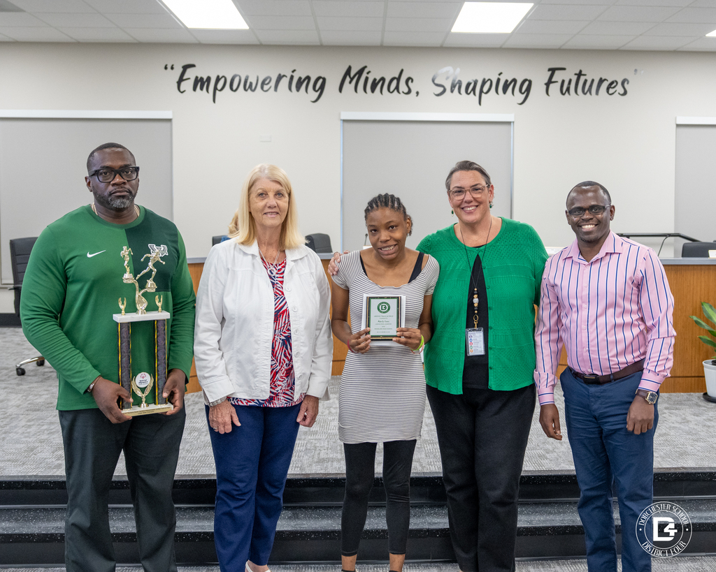 Two Unified Track & Field coaches stand with a district representative while holding championship plaques during the May 19 DD4 Board Meeting.