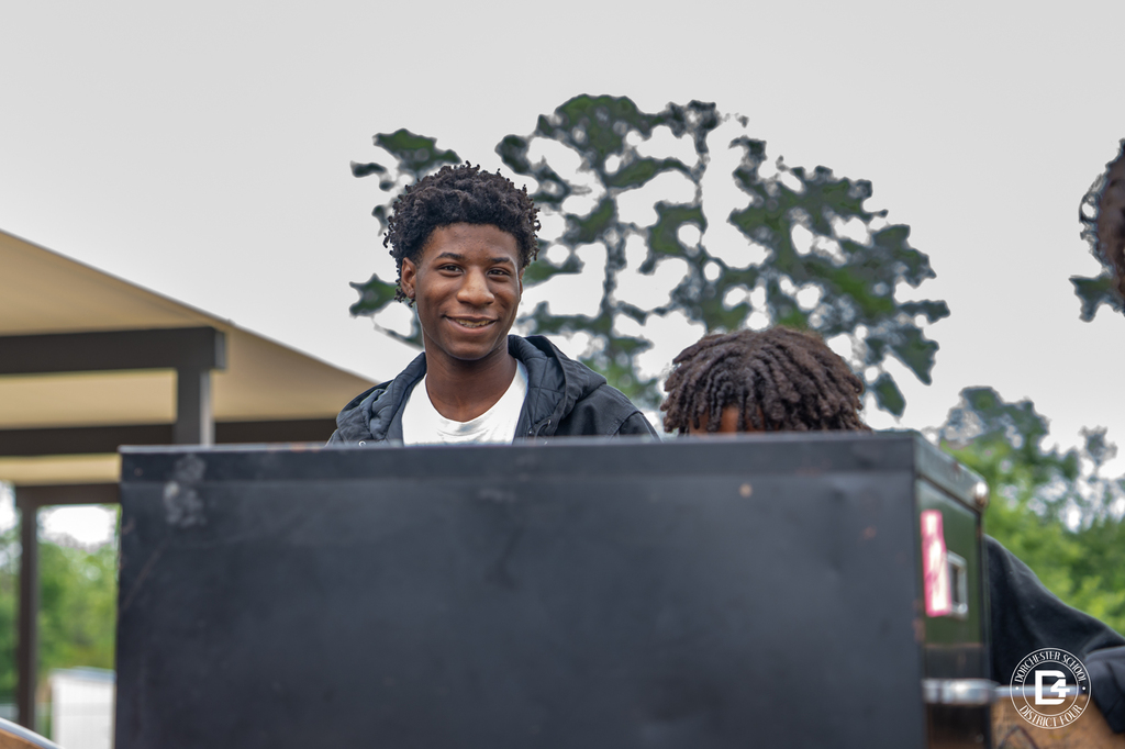 Student smiles while helping load furniture during the district's summer work program.