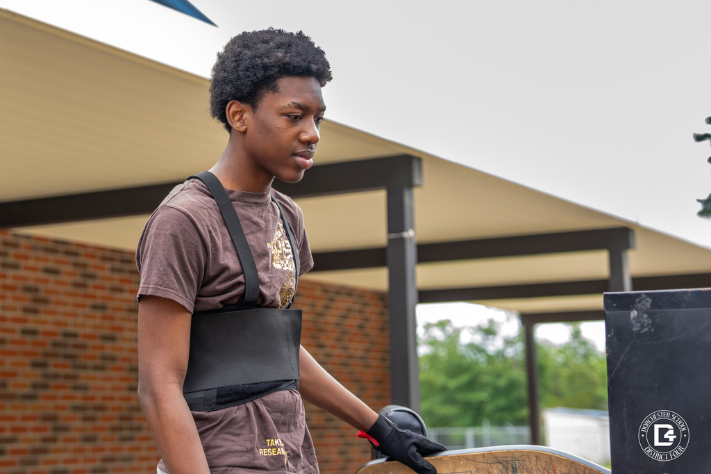 Student wearing a lifting belt moves furniture as part of summer school preparations.