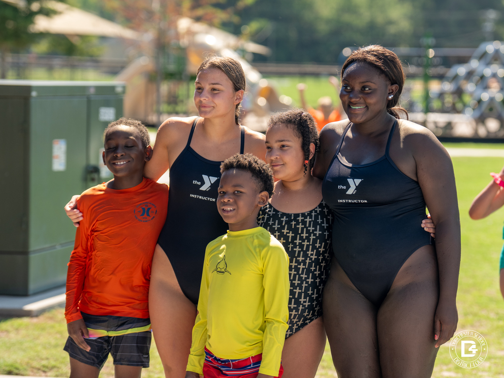 YMCA instructors pose with students after completing the Splash Into Safety water safety program.