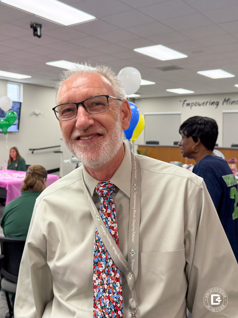 A DD4 administrator smiles while attending the district's Food Services in-service with staff gathered in the background.