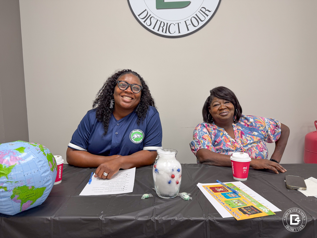 Two DD4 Food Services employees smile while seated at a themed table during the district's Food Services in-service.