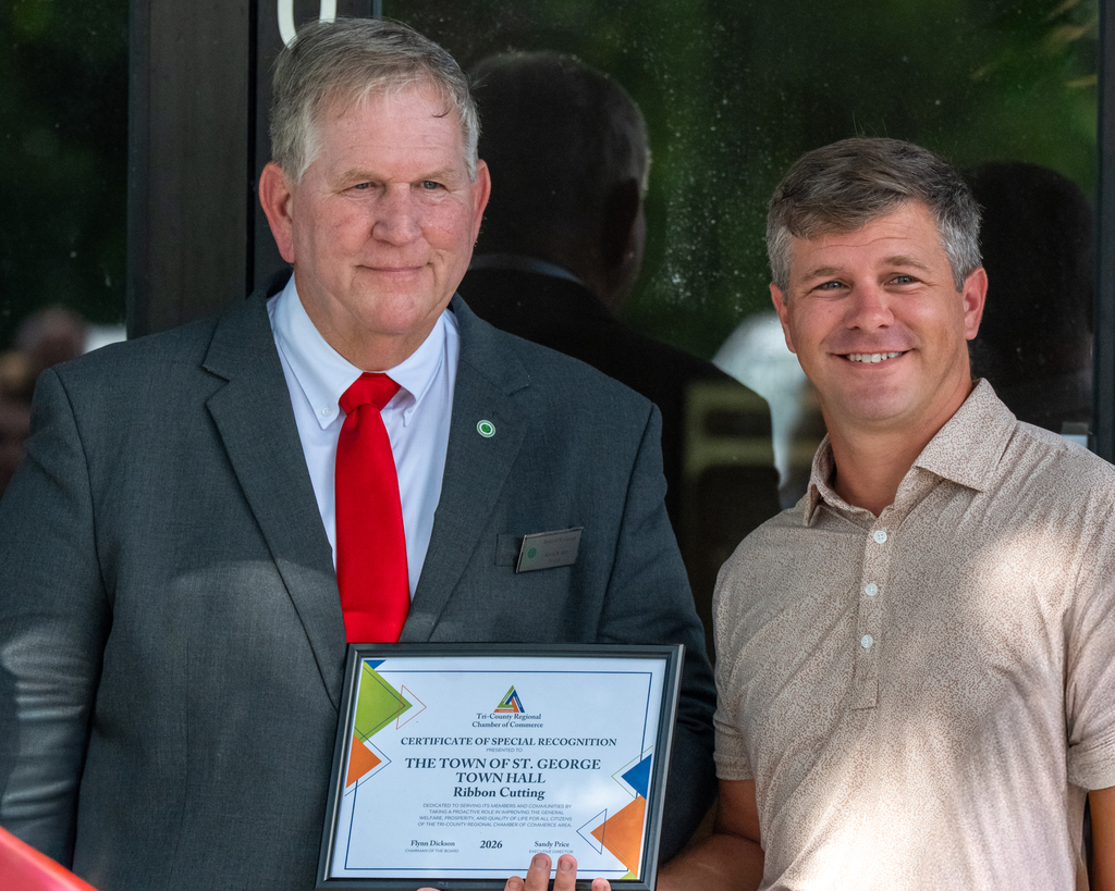 Mayor Kevin Hart standing beside a man in a tan polo shirt, holding a framed Certificate of Special Recognition from the Tri-County Regional Chamber of Commerce presented to the Town of St. George for its Town Hall ribbon cutting.