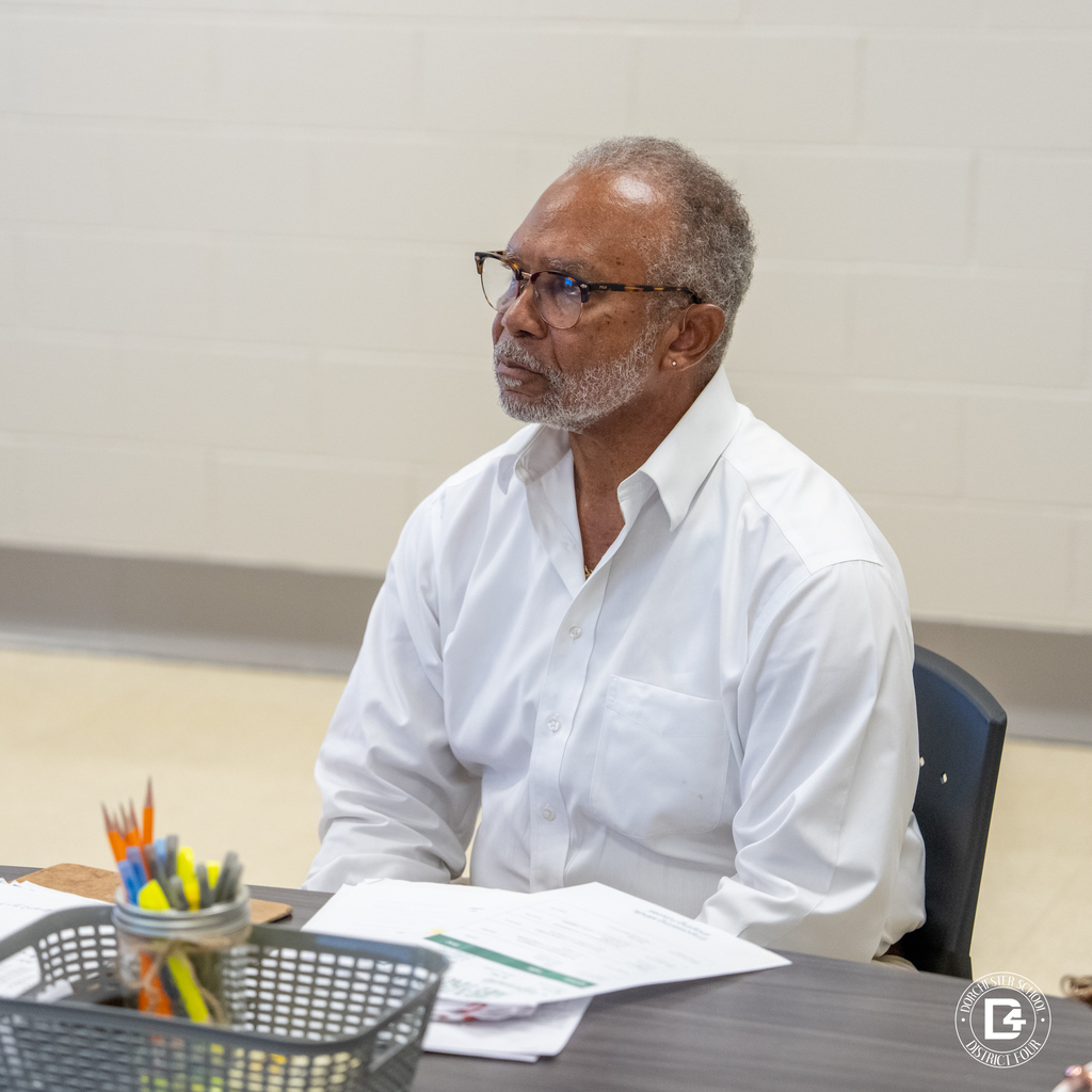 Man in a white shirt seated and participating in the mentoring program orientation.