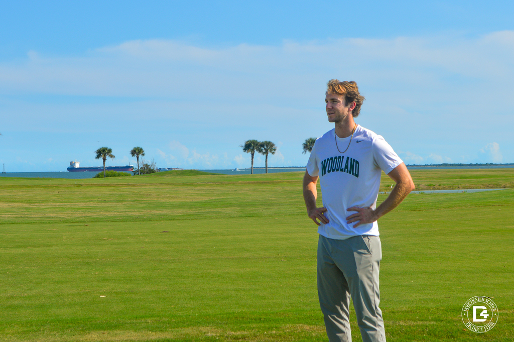 Woodland High School golf coach stands on the course wearing a Woodland shirt.