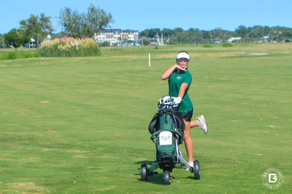 Woodland High School golfer poses beside her golf bag on the course.