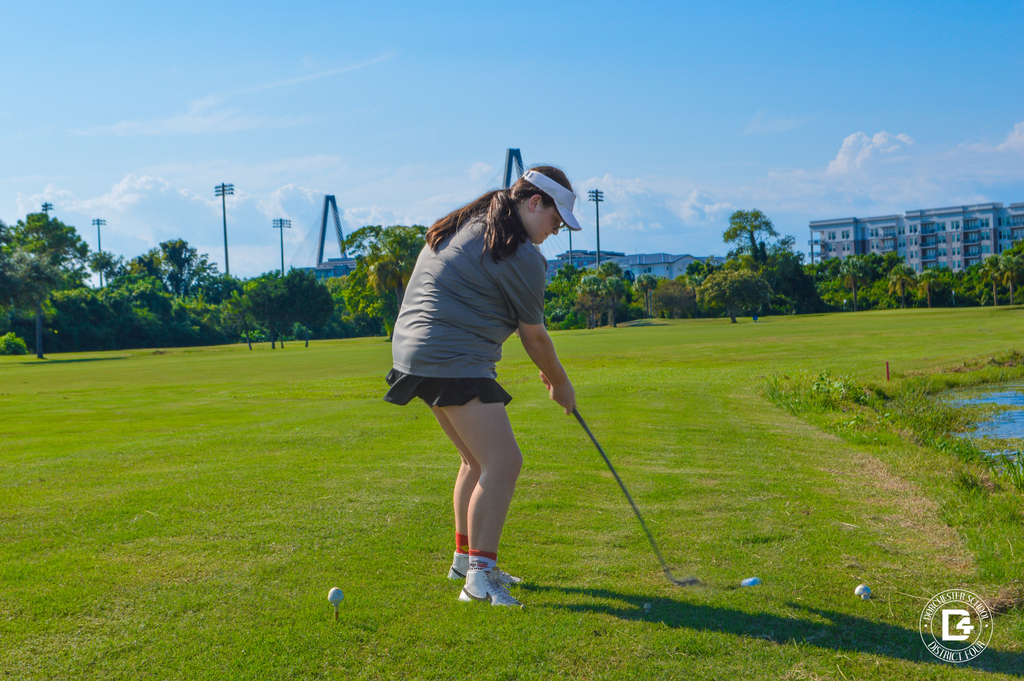 oodland High School golfer swings at a golf ball near the edge of the course.