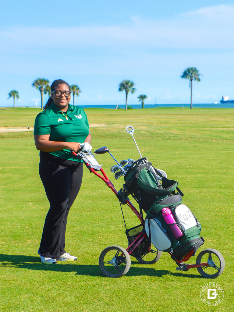 Woodland High School golfer stands beside a golf bag on the course.