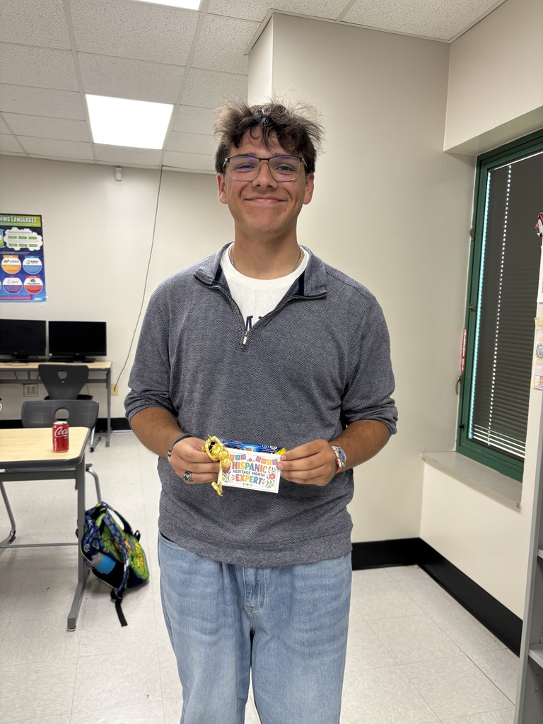 Woodland student smiles while holding a Hispanic Heritage Month trivia prize.