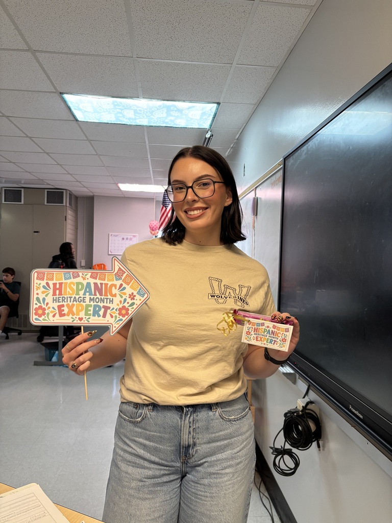 Woodland staff member smiles while holding a Hispanic Heritage Month trivia prize.