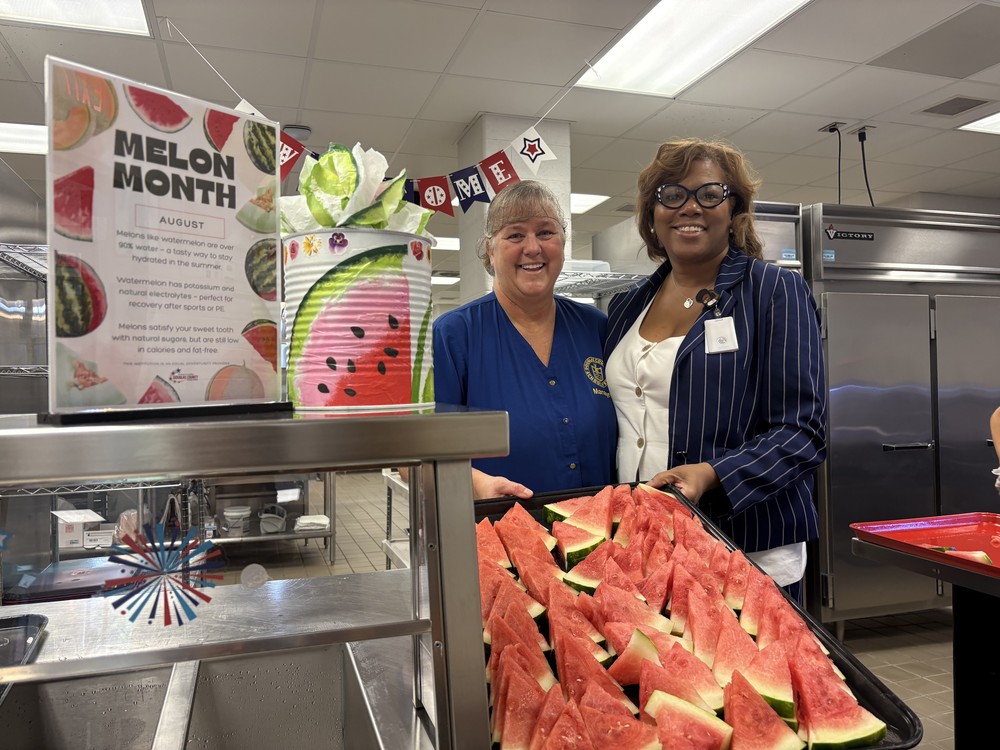 Executive Director of School Nutrition Danielle Freeman and a cafeteria manager pose with a tray of watermelon.