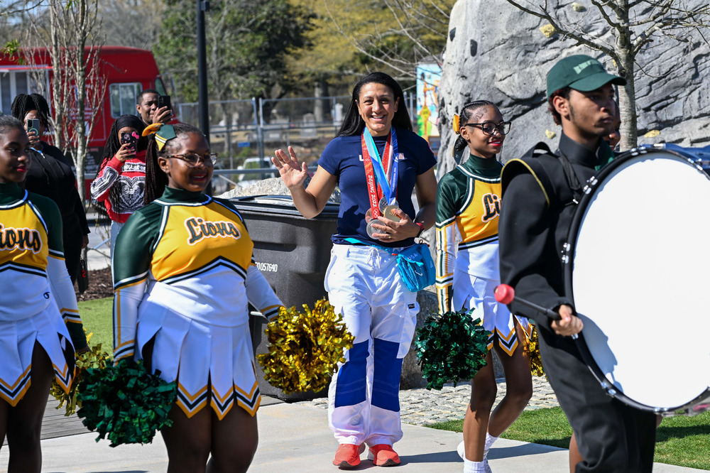 Olympic gold medalist Elana Meyers Taylor waves as she makes her way to the stage while Lithia Springs High cheerleaders and drumline members perform.