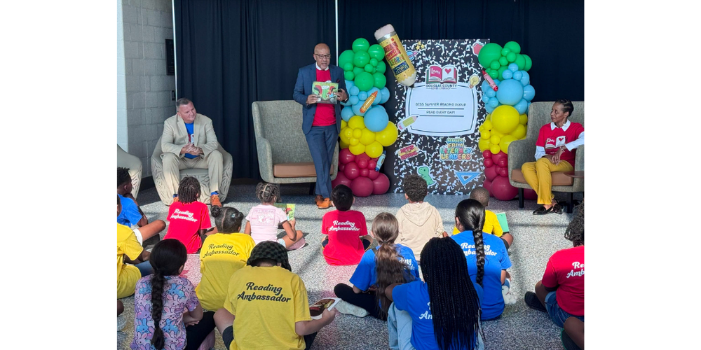 Superintendent Dr. Trent North reads to students at the final Summer Reading Pop-Up as Board Chair Glenn Easterwood and Vice Chair Michelle Simmons look on.