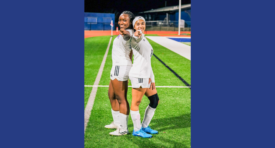 Two DCHS girls soccer players point to the camera.