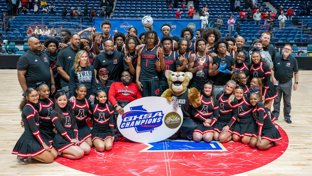 Alexander's boys basketball team and cheerleaders pose with the state championship trophy after their win on March 13, 2026.