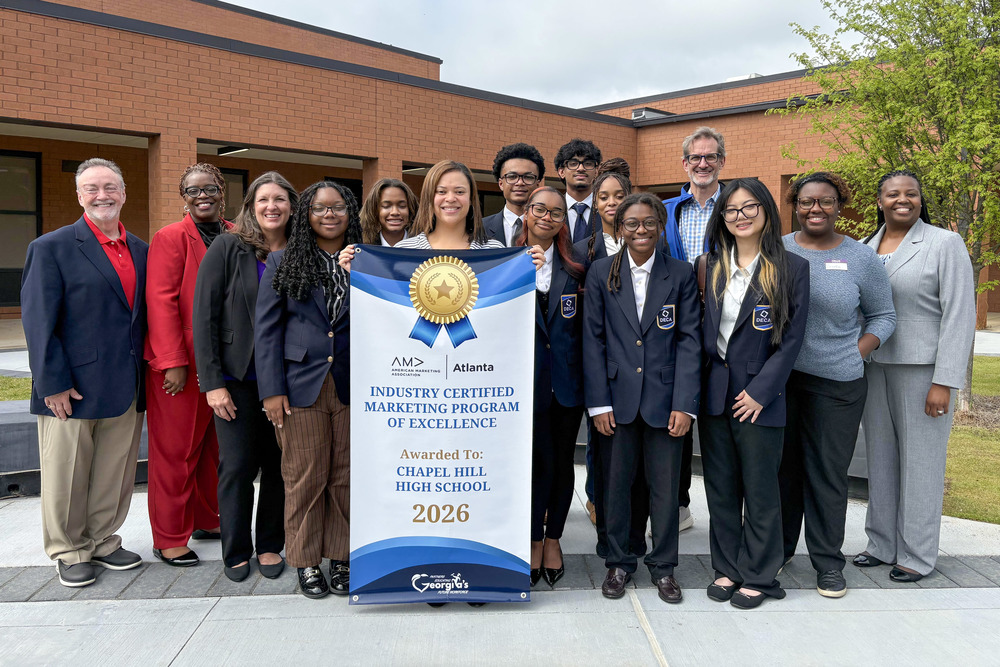 Chapel Hill High students, staff and DCSS Executive Director of CTAE/6-12 Curriculum Tekmekia Gilchrist are pictured in front of the school with the school's new Industry Certified Marketing Program of Excellence banner.l