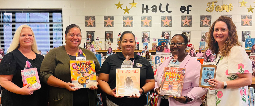 CHES teachers and administrators hold up books.