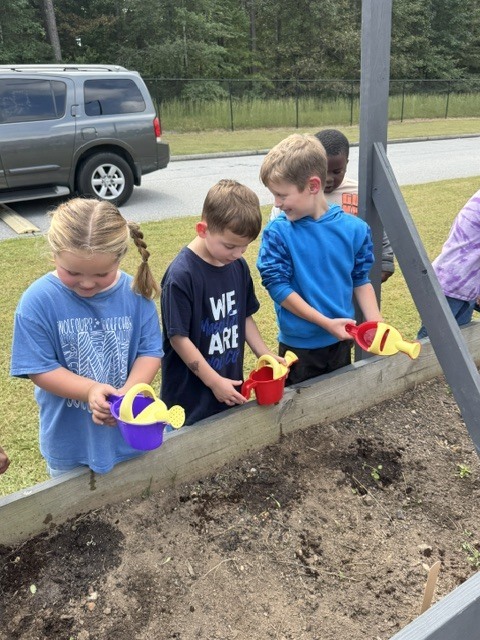 1st grade students planting and watering garden