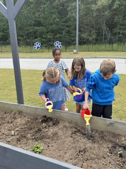 1st grade students planting and watering garden